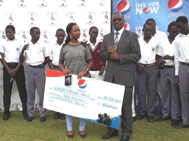 Pepsi Brand Executive Tracy Kakuru (with dummy cheque) watches on as the Uganda Cricket Association CEO, Justine Ligyalingi,
